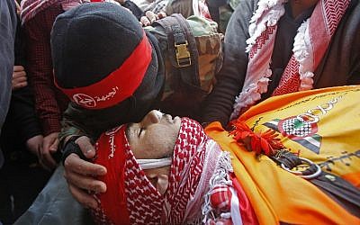 A member of the Popular Front for the Liberation of Palestine terror group kisses the head of Sajid Muzher, 17, after he was reported killed by Israeli fire during clashes in the Dheisheh refugee camp near the West Bank city  of Bethlehem, during his funeral on March 27, 2019. (Musa Al Shaer/AFP)