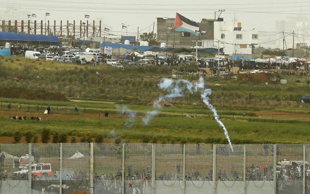This picture taken on March 30, 2019, in Kibbutz Nahal Oz across the border from the Gaza Strip shows a tear gas canister falling among Palestinians near the security fence as they mark the first anniversary of the 'March of Return' protests. (Jack Guez/AFP)