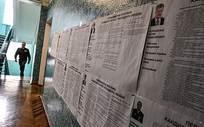 A security officer walks past voting information boards on candidates at a polling station in the center of Kiev on March 30, 2019 ahead of the Ukrainian presidential election on March 30. (Vasily Maximov/AFP)