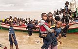 In this photo supplied by the Red Cross Red Crescent Climate Center, survivors of Cyclone Idai arrive by rescue boat in Beira, Mozambique, March 21, 2019. (Denis Onyodi - Red Cross Red Crescent Climate Center via AP)