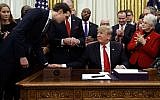 White House senior adviser Jared Kushner, left, talks with US President Donald Trump, seated, during a signing ceremony for criminal justice reform legislation in the Oval Office of the White House, in Washington, December 21, 2018. (Evan Vucci/AP)