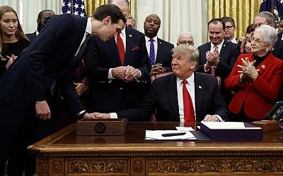 White House senior adviser Jared Kushner, left, talks with US President Donald Trump, seated, during a signing ceremony for criminal justice reform legislation in the Oval Office of the White House, in Washington, December 21, 2018. (Evan Vucci/AP)