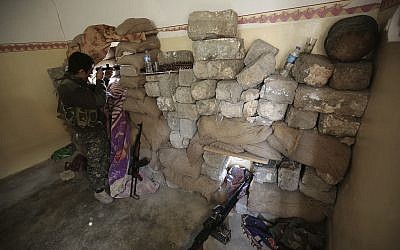 In this Jan. 29, 2015 file photo, a fighter of the Turkey-based Kurdish Workers' Party (PKK) uses his binoculars to look towards the Islamic State Group's base in the city of Sinjar, northern Iraq. (AP /Bram Janssen)