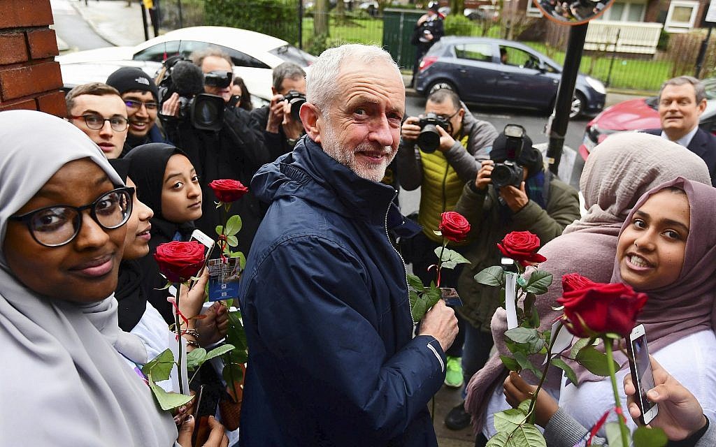 Britain's main opposition Labour Party leader Jeremy Corbyn is presented with flowers at the Finsbury Park Mosque in north London, during his visit on the annual Mosque open day, Sunday March 3, 2019. British police detained a man after Corbyn was hit by an egg during his visit to the Mosque Sunday, and the man charged with assault is due to appear in court Tuesday. (Victoria Jones/PA via AP)