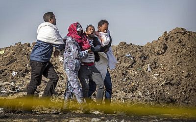 A grieving relative who lost his wife in the crash is helped by a member of security forces and others at the crash site of the Ethiopian Airlines Boeing 737 Max 8, March 13, 2019. (AP/Mulugeta Ayene)