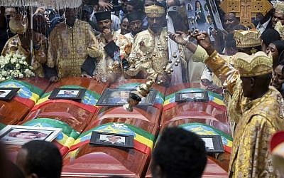 Priests swing incense over empty caskets draped with the national flag at a mass funeral at Holy Trinity Cathedral in Addis Ababa, March 17, 2019. Thousands of Ethiopians turned out to a mass funeral ceremony a week after the Ethiopian Airlines plane crash in which 157 people died. (AP Photo/Mulugeta Ayene)