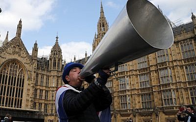 A pro EU protester shouts through a megaphone at the Houses of Parliament in London, Wednesday, March 27, 2019 as British lawmakers were preparing to vote on alternatives for leaving the European Union. (AP Photo/Frank Augstein)