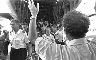 Israeli Foreign Minister Yigal Allon (back to camera) welcoming the rescued Air France passengers and crew including pilot Michel Bacos (left) coming off an Israel Air Force Hercules plane at Ben Gurion Airport, July, 1976 (Moshe Milner, Israel Government Press Office)