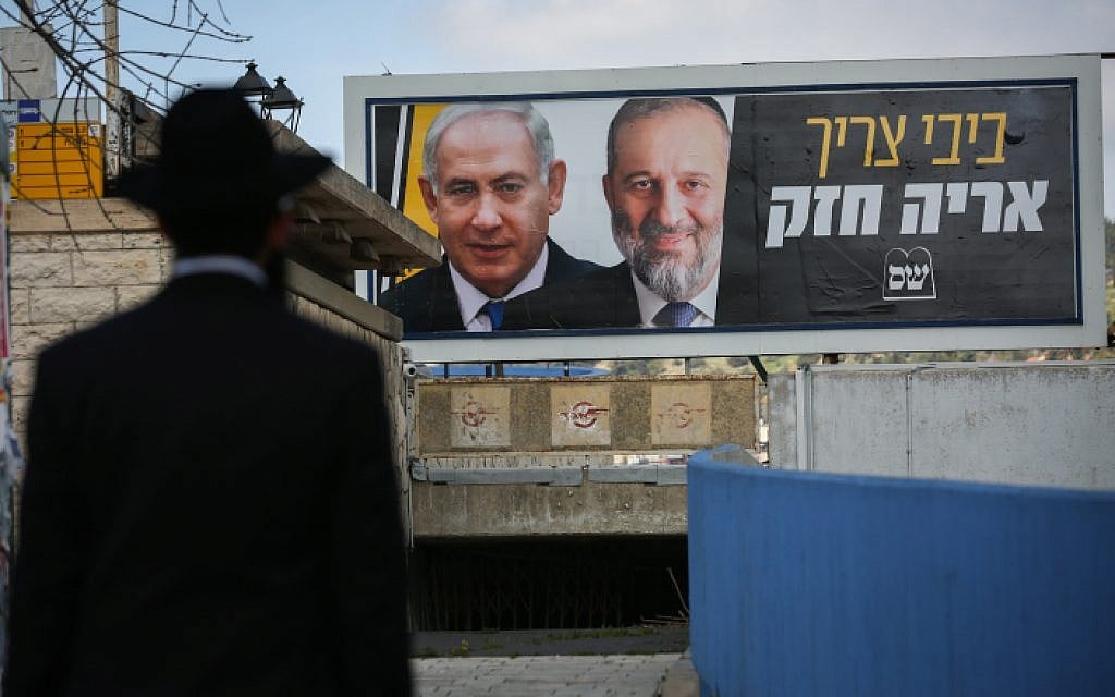 An ultra-Orthodox Jewish man near a billboard with pictures of Prime Minister Benjamin Netanyahu and Shas head Aryeh Deri, as part of the Shas election campaign, in Safed, March 10, 2019. (David Cohen/Flash90) An ultra-Orthodox Jewish man near a billboard with pictures of Prime Minister Benjamin Netanyahu and Shas head Aryeh Deri, as part of the Shas election campaign, in Safed, March 10, 2019. (David Cohen/Flash90)