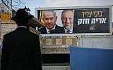 An ultra-Orthodox Jewish man near a billboard with pictures of Prime Minister Benjamin Netanyahu and Shas head Aryeh Deri, as part of the Shas election campaign, in Safed, March 10, 2019. (David Cohen/Flash90)