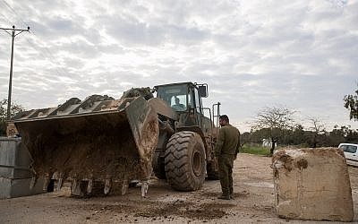 IDF soldiers stand by a military bulldozer moving concrete barricades to open a road that was shuttered by the army a day earlier near the Gaza border, on March 26, 2018. (Yonatan Sindel/Flash90)