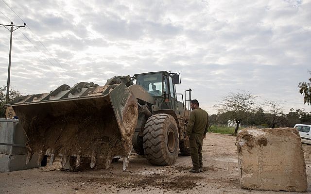 IDF soldiers stand by a military bulldozer moving concrete barricades to open a road that was shuttered by the army a day earlier near the Gaza border, on March 26, 2018. (Yonatan Sindel/Flash90) IDF soldiers stand by a military bulldozer moving concrete barricades to open a road that was shuttered by the army a day earlier near the Gaza border, on March 26, 2018. (Yonatan Sindel/Flash90)