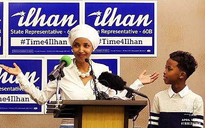 Then candidate for Minnesota Rep. Ilhan Omar campaigning in front of '#Time4Ilhan' posters. (Courtesy Norah Shapiro/ Chris Newberry)