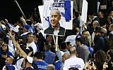Supporters of Likud wave party and national flags along with a sign showing Prime Minister Benjamin Netanyahu as they gather at the party's headquarters in Tel Aviv on election night early on April 10, 2019. (Jack GUEZ / AFP)