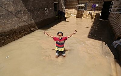 An Iranian child gestures for the camera at a flooded house in the city of Hamidiyeh, in Iran's Khuzestan province, on April 10, 2019.(ATTA KENARE / AFP)