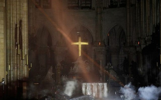Smoke rises around the alter in front of the cross inside the Notre-Dame Cathedral as the fire continued to burn on April 16, 2019 in Paris. (Photo by PHILIPPE WOJAZER / POOL / AFP)
