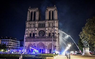 Firefighters gather at the facade of the Notre-Dame de Paris Cathedral as flames engulf the roof of the cathedral on April 15, 2019, in the French capital Paris. (STEPHANE DE SAKUTIN / AFP)