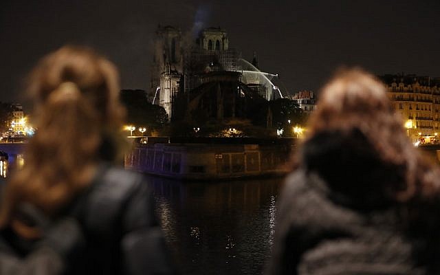 Bystanders look on as flames and smoke billow from the roof at Notre-Dame Cathedral in Paris early on April 16, 2019. (Zakaria ABDELKAFI / AFP) Bystanders look on as flames and smoke billow from the roof at Notre-Dame Cathedral in Paris early on April 16, 2019. (Zakaria ABDELKAFI / AFP)