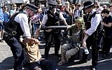 Police officers move climate change activists with their hands glued to a pipe as they continue to block the road at Oxford Circus in London on April 20, 2019. (Niklas HALLE'N / AFP)