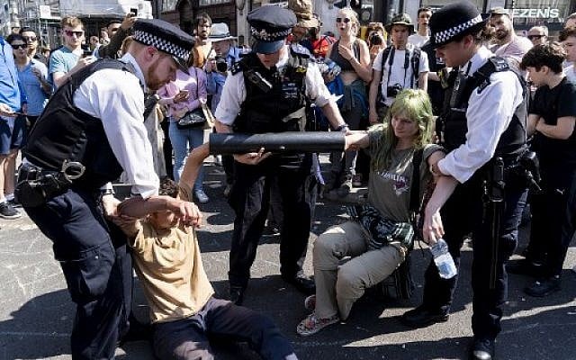 Police officers move climate change activists with their hands glued to a pipe as they continue to block the road at Oxford Circus in London on April 20, 2019. (Niklas HALLE'N / AFP) Police officers move climate change activists with their hands glued to a pipe as they continue to block the road at Oxford Circus in London on April 20, 2019. (Niklas HALLE'N / AFP)
