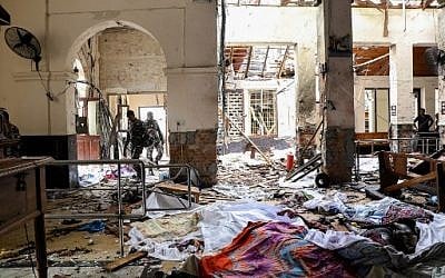Sri Lankan security personnel walk next to dead bodies on the floor amid blast debris at St. Anthony's Shrine, following an explosion in the church in Kochchikade in Colombo, on April 21, 2019. (ISHARA S. KODIKARA/ AFP)