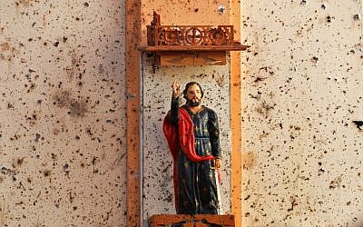 A statue is pictured next to shrapnel marks at St. Sebastian's Church in Negombo on April 22, 2019, a day after the building was hit as part of a series of bomb blasts targeting churches and luxury hotels in Sri Lanka. (Photo by ISHARA S. KODIKARA / AFP)