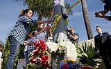 A woman and a young girl place notes on a light post near flowers across the street from the Chabad of Poway Synagogue after a shooting on April 27, 2019 in Poway, California. (SANDY HUFFAKER / AFP)
