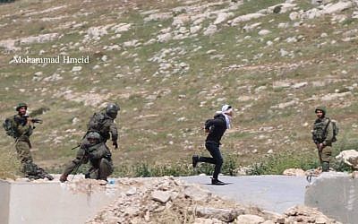 An IDF soldier chases a Palestinian suspect as he tries to escape in the West Bank town of Tuqu on April 18, 2019. (Mohammad Hmeid)