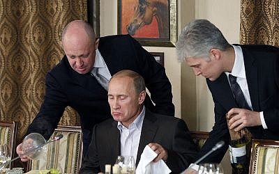 In this Nov. 11, 2011 photo, Yevgeny Prigozhin, left, serves food to Russian Prime Minister Vladimir Putin, center, during dinner at Prigozhin's restaurant outside Moscow, Russia (AP Photo/Misha Japaridze, Pool, File)