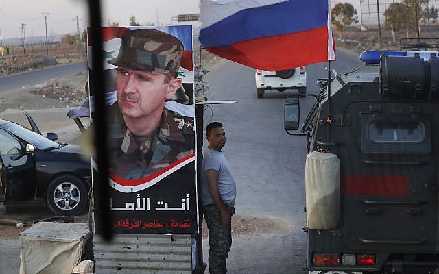 Syrian army soldier stands at a check-point as Russian military police vehicle, right, passes by near the village of Almajdiyeh, Syria, Tuesday, Aug. 14, 2018. (AP/Sergei Grits) Syrian army soldier stands at a check-point as Russian military police vehicle, right, passes by near the village of Almajdiyeh, Syria, Tuesday, Aug. 14, 2018. (AP/Sergei Grits)