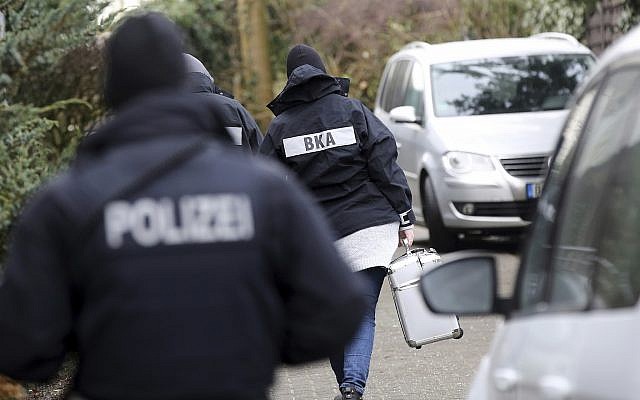 Illustrative: Police officer walk between cars during a raid in the village Meldorf, Germany, January 30, 2019. (Bodo Marks/dpa via AP) Illustrative: Police officer walk between cars during a raid in the village Meldorf, Germany, January 30, 2019. (Bodo Marks/dpa via AP)