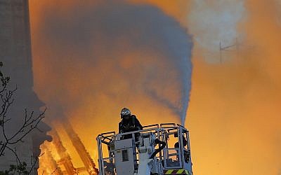A fire fighter uses a hose as Notre Dame cathedral is burning in Paris, Monday, April 15, 2019. (AP /Francois Mori)