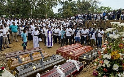 A priest conducts a mass burial for Easter Sunday bomb blast victims in Negombo, Sri Lanka on April 24, 2019. (AP Photo/Gemunu Amarasinghe)