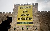 Greenpeace activists rappel down the walls of the Jerusalem's Old City, during a protest on April 1, 2019, to hang a banner saying 'Bolsonaro Stop Amazon Destruction' during the visit of Brazilian President Jair Bolsonaro in Israel (Yonatan Sindel/Flash90)