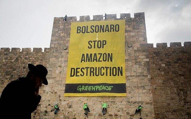 Greenpeace activists rappel down the walls of the Jerusalem's Old City, during a protest on April 1, 2019, to hang a banner saying 'Bolsonaro Stop Amazon Destruction' during the visit of Brazilian President Jair Bolsonaro in Israel (Yonatan Sindel/Flash90) Greenpeace activists rappel down the walls of the Jerusalem's Old City, during a protest on April 1, 2019, to hang a banner saying 'Bolsonaro Stop Amazon Destruction' during the visit of Brazilian President Jair Bolsonaro in Israel (Yonatan Sindel/Flash90)
