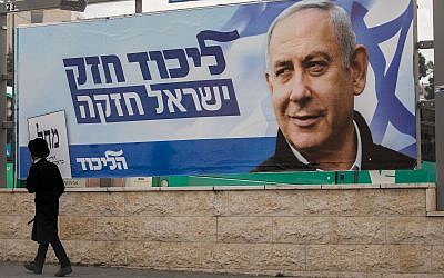 A man walks past an election campaign poster for Benjamin Netanyahu, prime minister and head of the Likud party in Jerusalem on April 2, 2019 (Yonatan Sindel/Flash90)