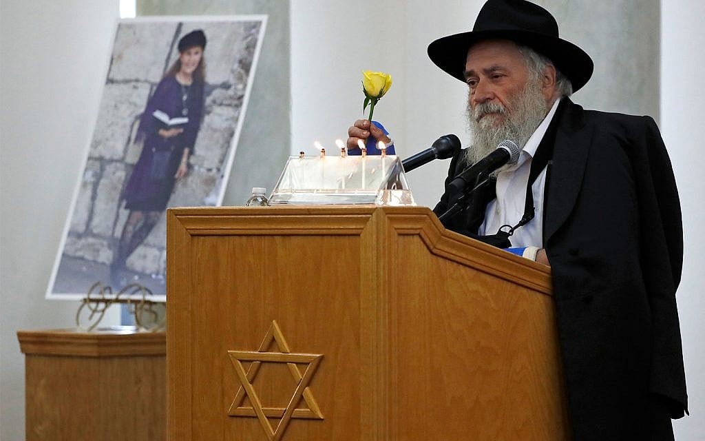 Yishoel Goldstein, Rabbi of Chabad of Poway, holds a yellow rose as he speaks Monday, April 29, 2019, at the funeral for Lori Gilbert-Kaye, who is pictured at left, in Poway, California. (AP Photo/Gregory Bull)