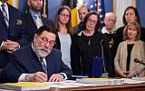 Pittsburgh Mayor Bill Peduto, surrounded by supporters and family members of Tree of Life synagogue shooting victims, signs three gun-control bills into law, April 9, 2019, at the City-County Building in downtown Pittsburgh. (Steph Chambers/Pittsburgh Post-Gazette via AP)