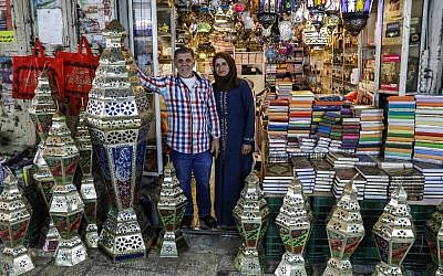 Palestinian craftsman Issam Zughair stands with his wife next to an assortment of Ramadan lanterns in the entrance of his shop in the Old City of Jerusalem on May 2, 2019 (AHMAD GHARABLI / AFP)
