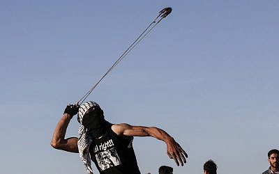 Illustrative: A Palestinian hurls stones at Israeli troops during clashes near the border with Israel, east of Gaza City, on May 10, 2019. (Said Khatib/AFP)