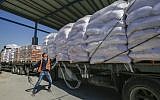 A Palestinian worker checks a truck carrying United Nations Relief and Work Agency (UNRWA) aid supplies that arrived through the Kerem Shalom crossing from Israel to the southern Gaza Strip city of Rafah, on May 12, 2019. (Said Khatib/AFP)