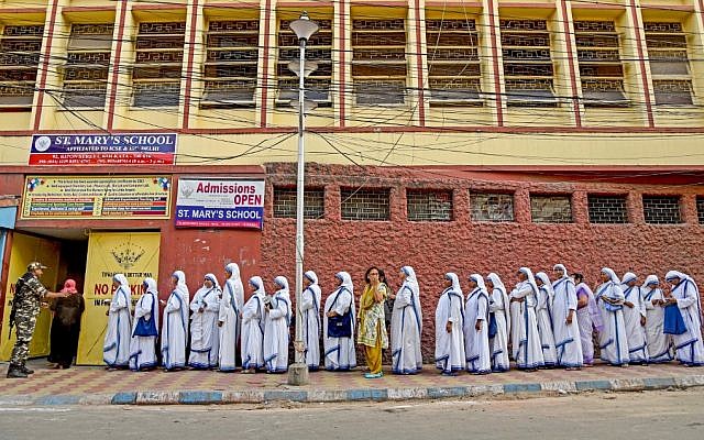 Indian nuns from the Mother Teresa Missionaries of Charities queue to cast their votes as a paramilitary force personnel stands guard at a polling station at St. Mary's School in Kolkata on May 19, 2019, during the 7th and final phase of India's general election. (Amit Datta / AFP)