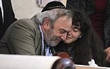 Howard Kaye, center, and his daughter Hannah Kaye, hug after the final letter is inked into the new Torah scroll dedicated to wife and mother Lori Kaye, who was killed when a gunman attacked the Chabad of Poway on April 27, 2019, during a celebration for the new scroll, foreground, at the synagogue on May 22, 2019, in Poway, California. (Hayne Palmour IV/The San Diego Union-Tribune via AP)
