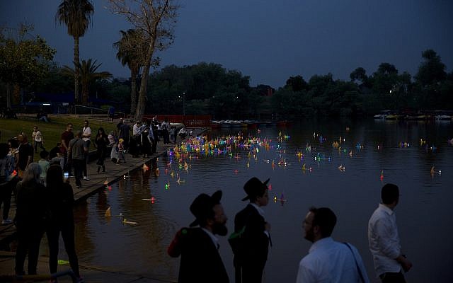 People look at floating handmade boats with the names of Nazi concentration camps, during a ceremony at Hayarkon park in Tel Aviv marking Holocaust Remembrance Day on May 1, 2019. (AP Photo/Oded Balilty)