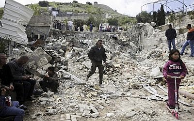 In this April 17, 2019 file photo, Palestinians watch a family house destroyed by Israeli authorities in East Jerusalem's neighborhood of Silwan. (AP Photo/Mahmoud Illean, File)
