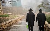 Illustrative: Ultra-Orthodox men walking in the rain and fog in Safed, December 18, 2018. (David Cohen/Flash90)