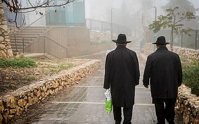 Illustrative: Ultra-Orthodox men walking in the rain and fog in Safed, December 18, 2018. (David Cohen/Flash90)