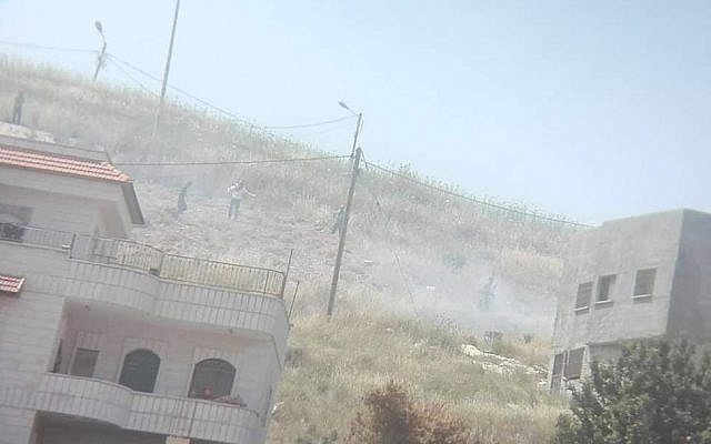 A photo from the Yesh Din rights group shows what it says are Israeli settlers by a fire they started near the northern West Bank village of Asira al-Qibliya on May 17, 2019. (Yesh Din)
