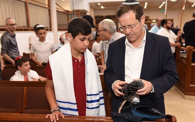 Then-Jewish Agency head Isaac Herzog helps a participant in a bar and bat mitzvah for deaf teens to unwrap his tefillin at the Nitzanim Synagogue in Jerusalem on May 20, 2019. (Nachshon Philipson) Then-Jewish Agency head Isaac Herzog helps a participant in a bar and bat mitzvah for deaf teens to unwrap his tefillin at the Nitzanim Synagogue in Jerusalem on May 20, 2019. (Nachshon Philipson)