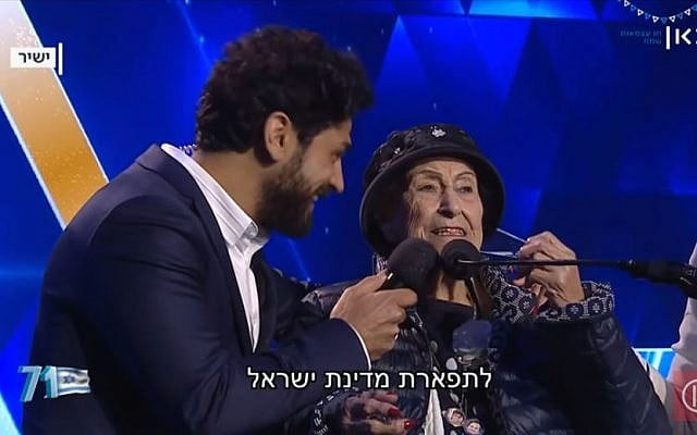 Host Aviv Alush, left, and torch-lighter Marie Nahmias, 93, at Israel's 71st Independence Day ceremony in Jerusalem, May 8, 2019. (Kan screen capture) Host Aviv Alush, left, and torch-lighter Marie Nahmias, 93, at Israel's 71st Independence Day ceremony in Jerusalem, May 8, 2019. (Kan screen capture)